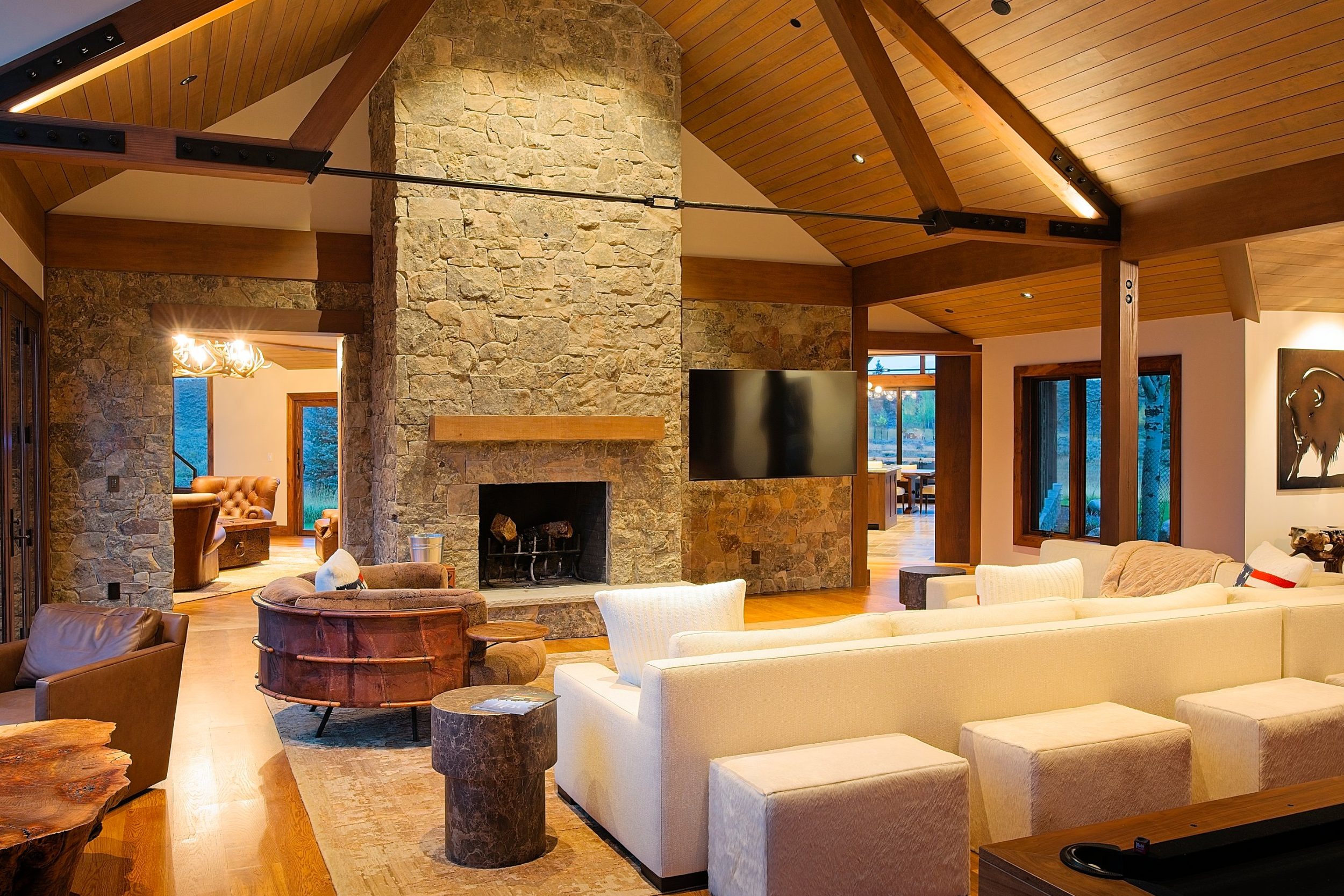 Great room with full-height stone fireplace and vaulted timber truss ceiling in a custom mountain home