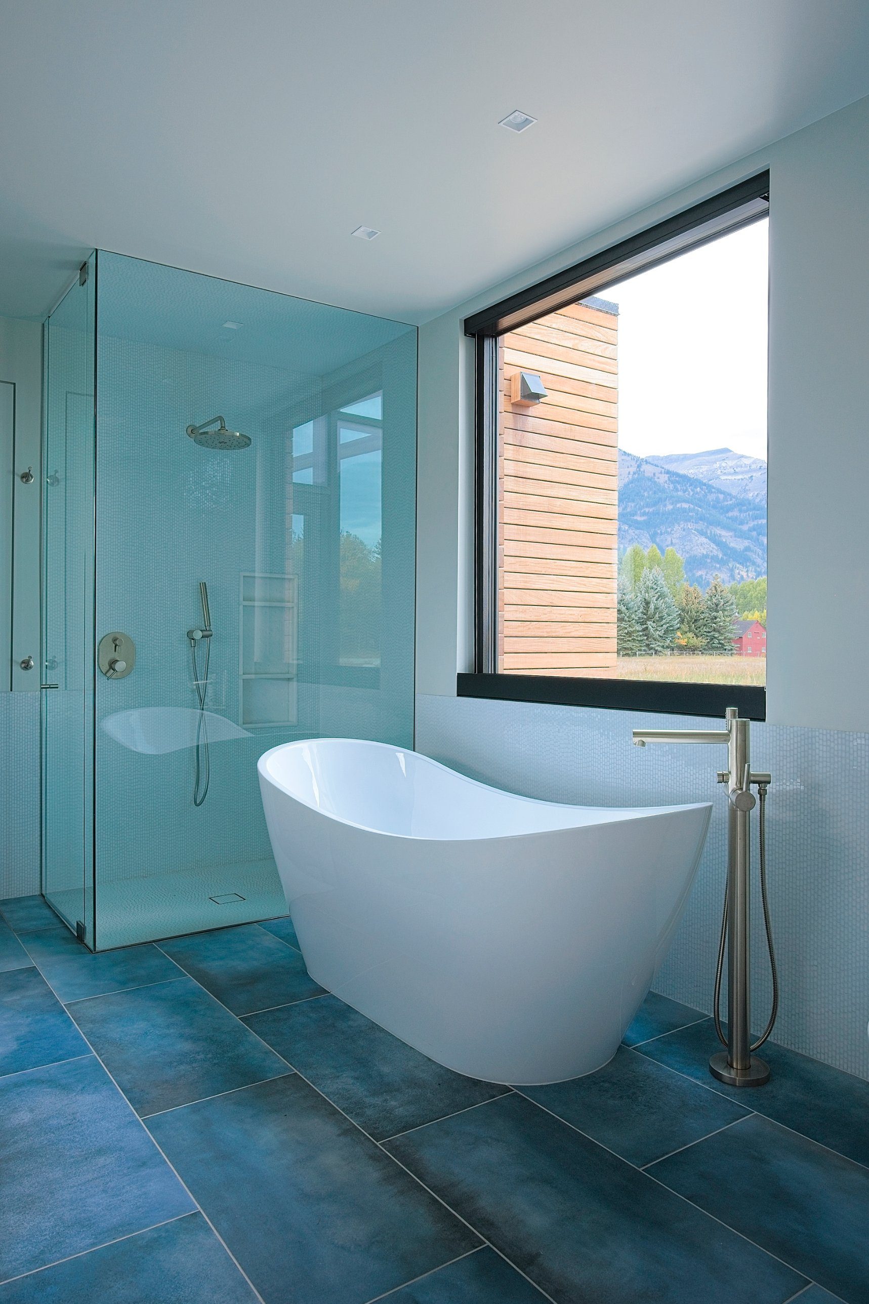 Bathroom with freestanding soaking tub, glass shower, and window to the mountains