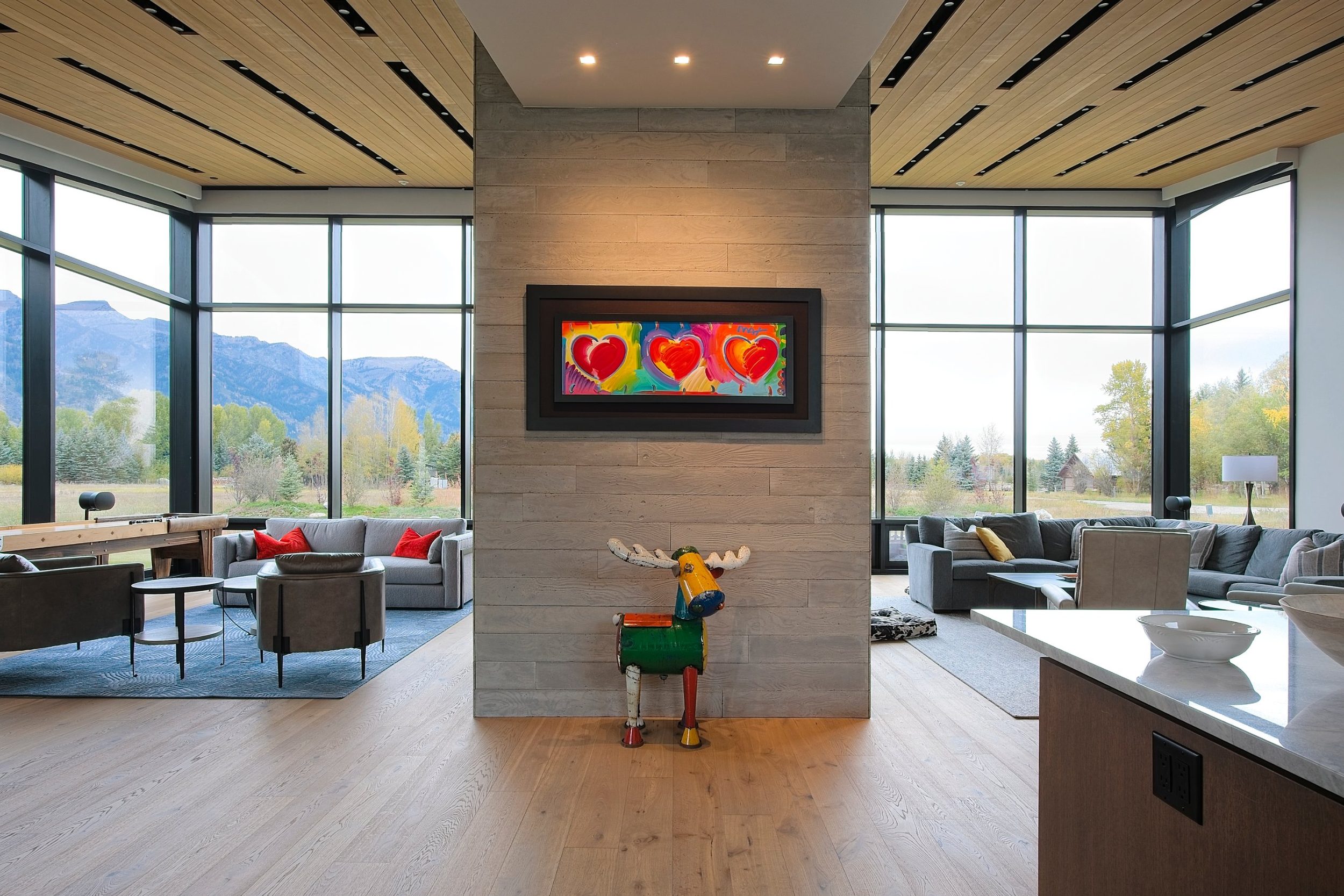 Open living space divided by a board-formed concrete wall, with glass walls on both sides