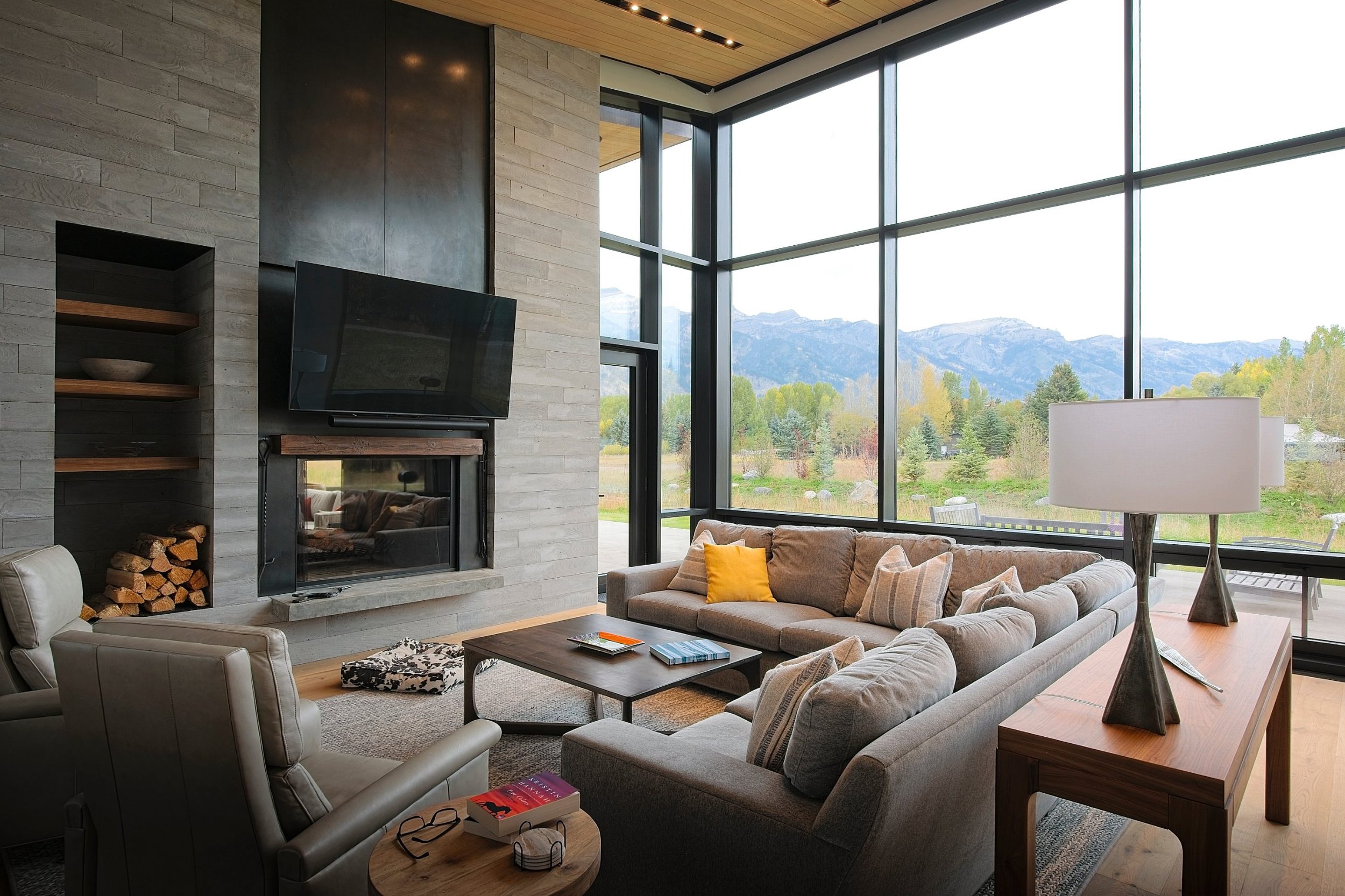 Living room with board-formed concrete fireplace wall and two-story windows facing the mountains